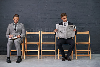 Buy stock photo Shot of a row of chairs with two businessmen seated slightly apart