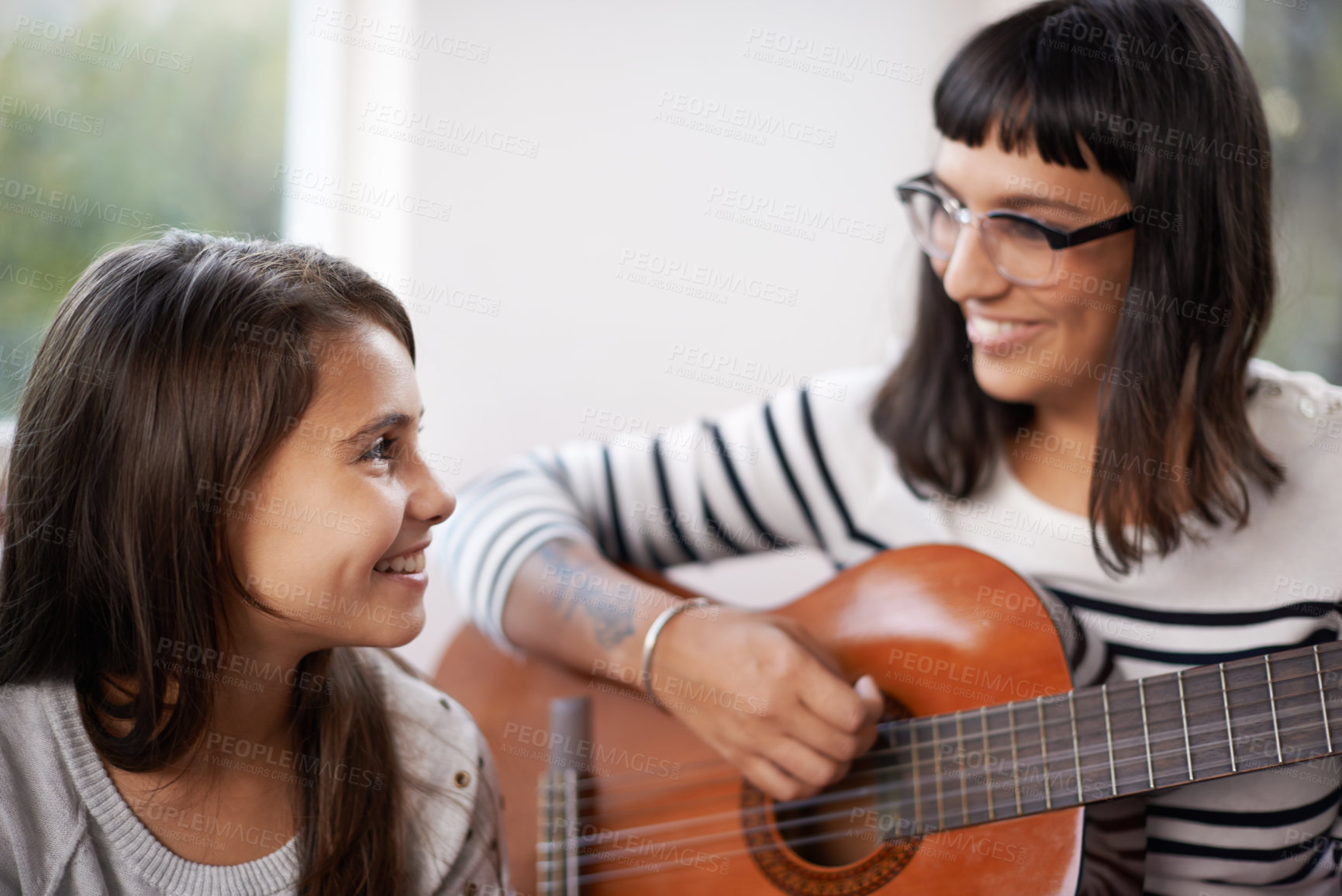 Buy stock photo Mother, music and guitar in living room for daughter, relaxing and enjoying together on couch. Bonding, woman and child with smile on sofa, entertainment and mom play with musical instrument