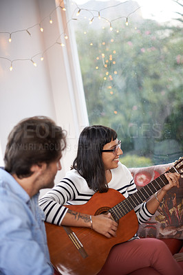 Buy stock photo Couple, woman and play guitar in living room for men, chilling and enjoying together on couch. Married, wife and husband with smile on sofa to bond, entertainment and listen to musical instrument