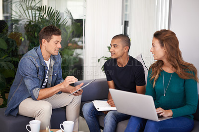 Buy stock photo A team of young business professionals using technology in an informal meeting