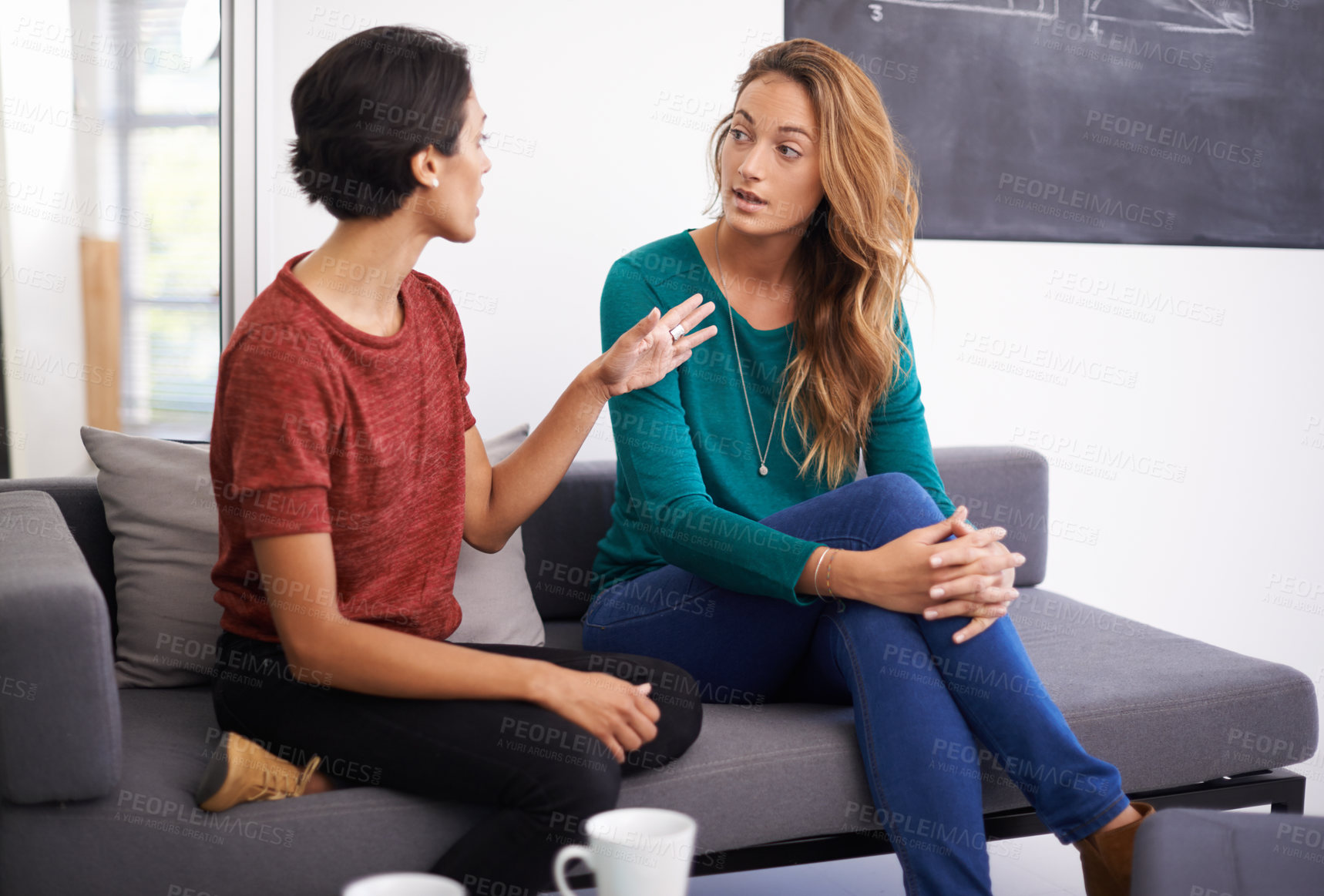 Buy stock photo Shot of two female professionals having a discussion in an informal office setting