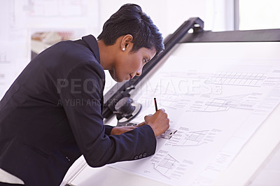 Buy stock photo Cropped shot of a female architect working on a building plan at a drawing board