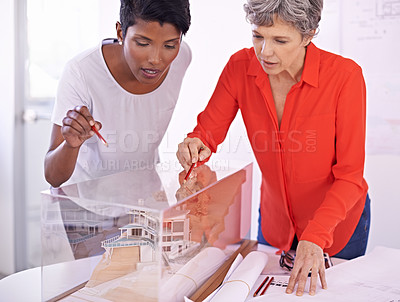 Buy stock photo Shot of two female architects discussing an architectural model