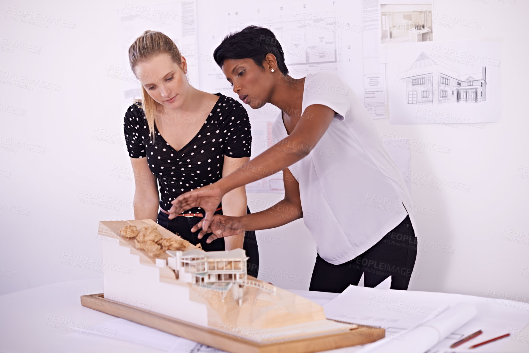 Buy stock photo Shot of two female architects discussing an architectural model