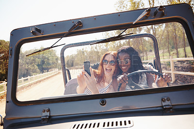 Buy stock photo Shot of two attractive young women snapping a selfie in the car