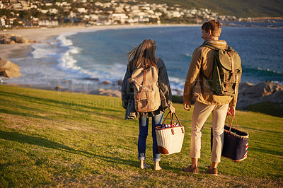 Buy stock photo Love, walking and couple on hike with ocean, sunset for tropical holiday adventure, relax and bonding together. Picnic, man and woman on romantic date on beach, nature and grass on vacation from back
