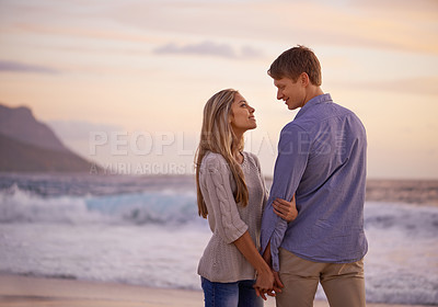 Buy stock photo Couple, holding hands and love in looking by water, ocean waves and peace for romance in relationship. People, beach and security in marriage, sea and travel together on vacation or holiday for date