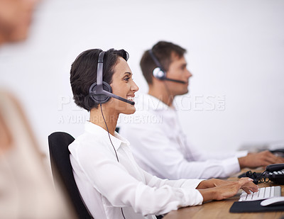 Buy stock photo Shot of two help desk operators wearing headsets and working at their computers
