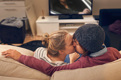 Buy stock photo Love, kiss and couple watching tv on a sofa with romance, fun or bonding at home together. Television, movies or people embrace in a living room with trust, support or film, video or Netflix in house
