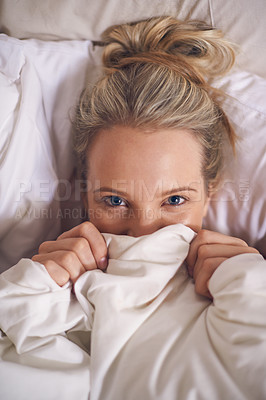 Buy stock photo A young woman peeking out from under her ned sheet with a frightened expression