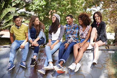 Buy stock photo Shot of a group of young friends hanging out at a skate park