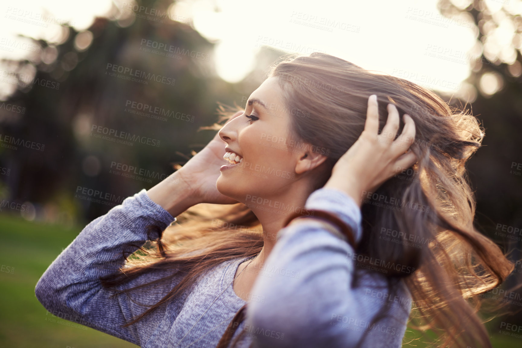 Buy stock photo A carefree young woman flinging her hair while outdoors