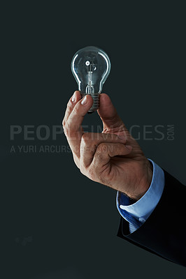 Buy stock photo Shot of a hand holding a lightbulb on a black background