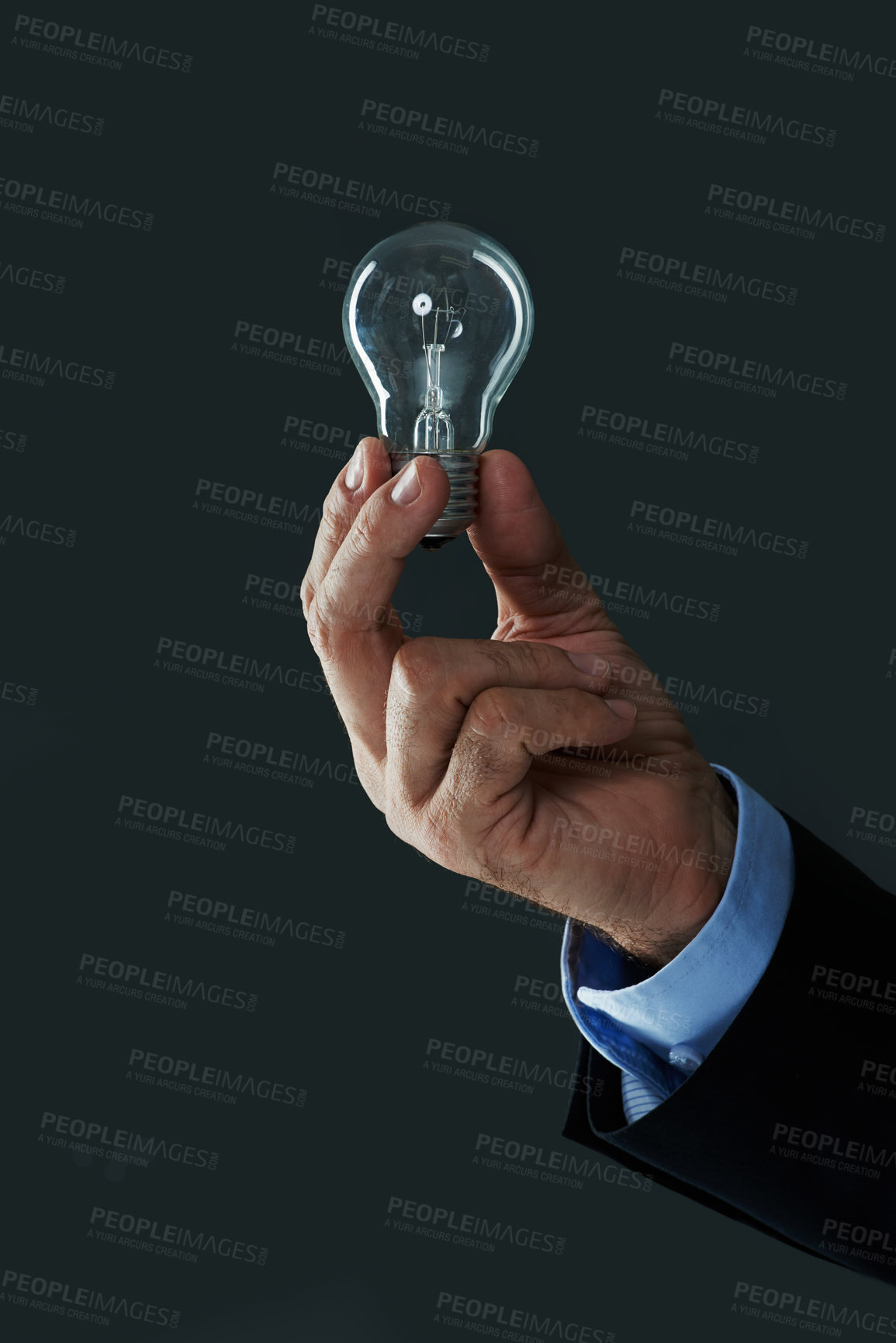Buy stock photo Shot of a hand holding a lightbulb on a black background
