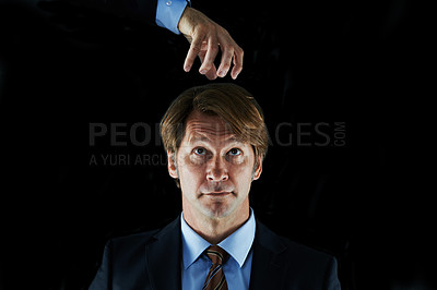 Buy stock photo Concept shot of a businessman with a hand hovering above him