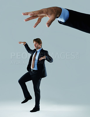 Buy stock photo Shot of a businessman being made to move like a puppet by a hand hovering above him