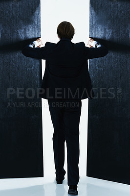 Buy stock photo Rear view shot of a businessman opening the doors of a dark room