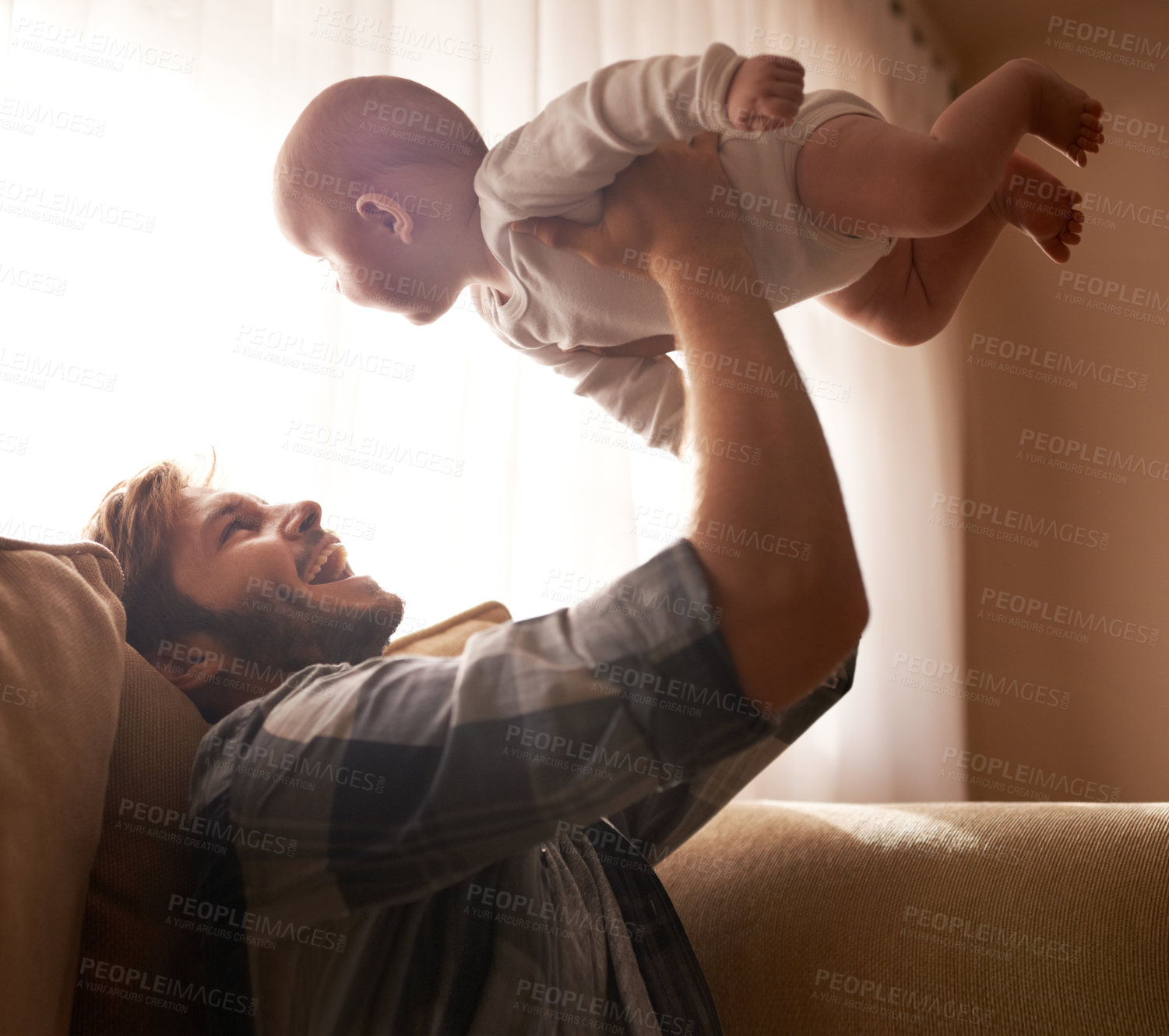 Buy stock photo Funny, father and lifting baby on sofa in home living room, playing or bonding together. Happy, care and dad holding infant, newborn or child on couch in lounge, having fun and enjoying quality time.
