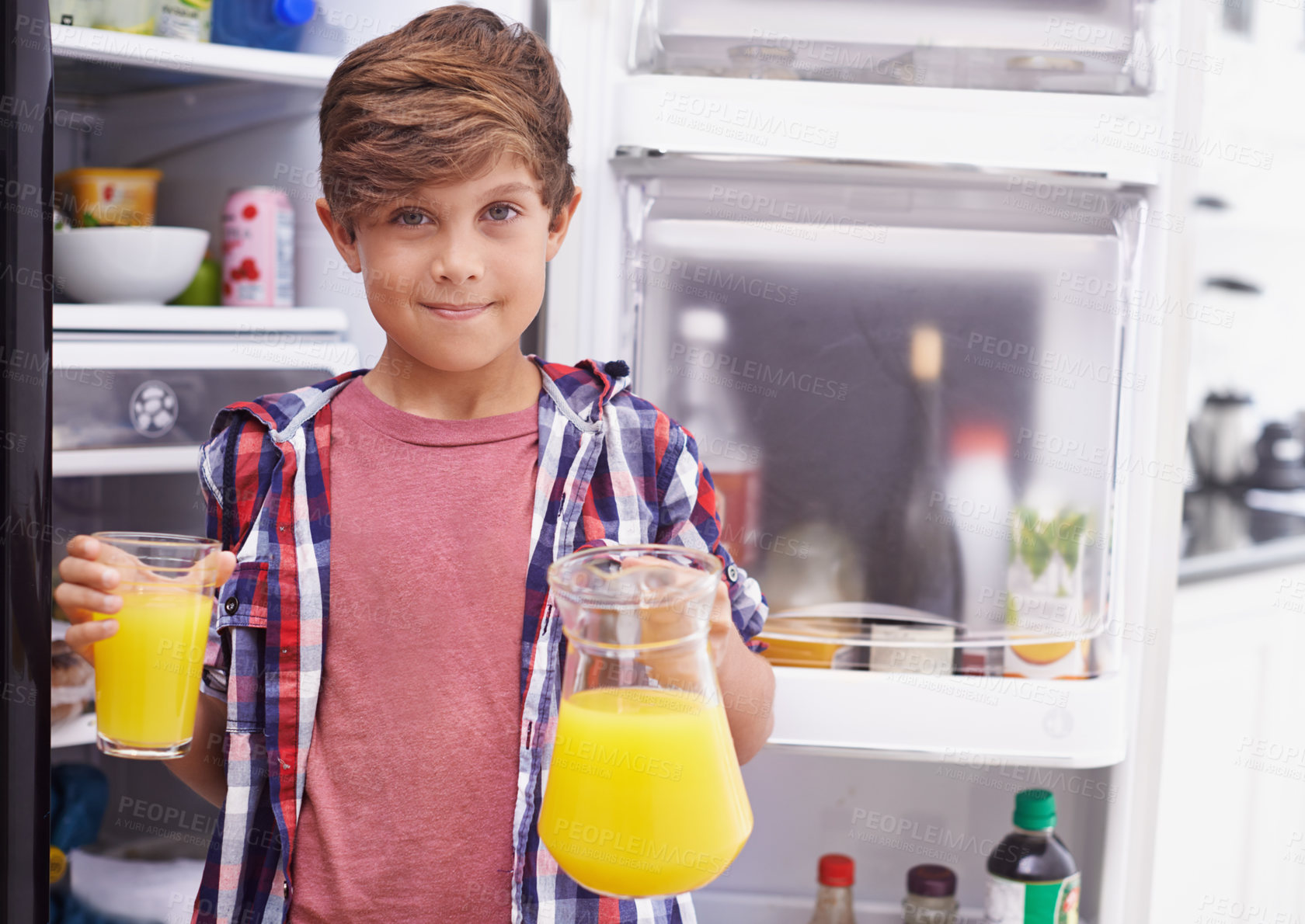 Buy stock photo Shot of a young boy standing in front of the fridge with some orange juice