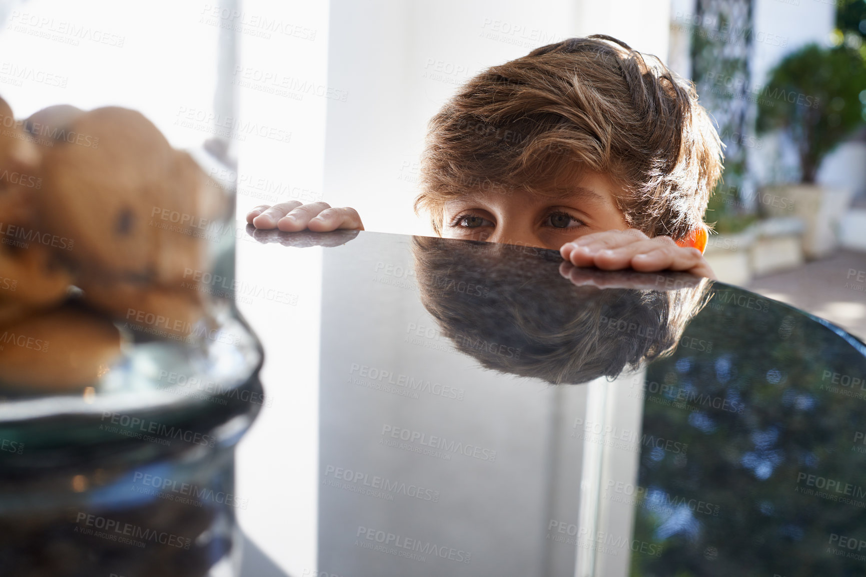 Buy stock photo A young boy eyeing the cookie jar on top of the kitchen counter