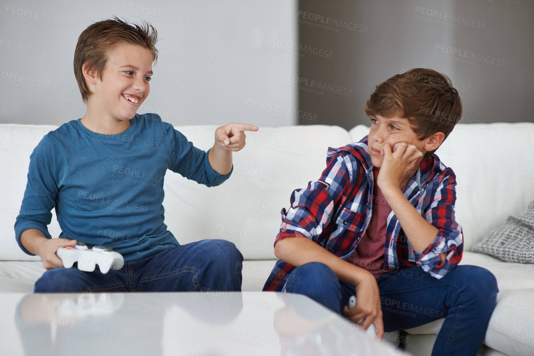 Buy stock photo Shot of a young boy laughing at his friend after beating him at a video game