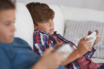 Buy stock photo Shot of two tired young boys sitting and playing video games