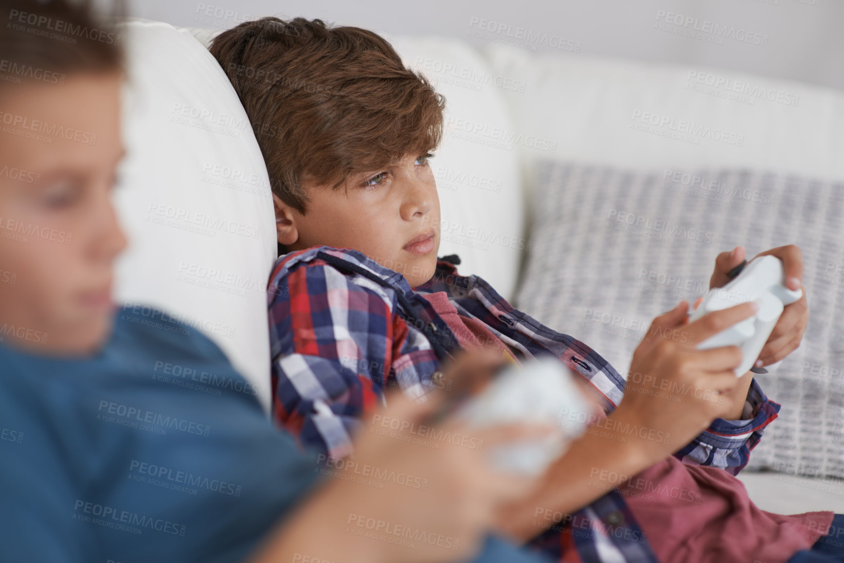 Buy stock photo Shot of two tired young boys sitting and playing video games