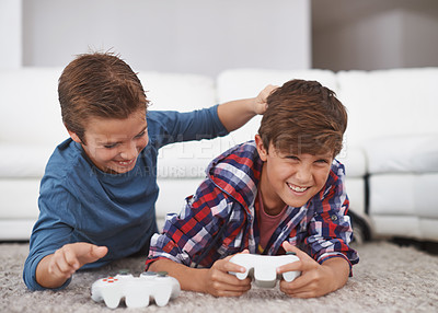 Buy stock photo Shot of two young boys teasing each other while playing video games