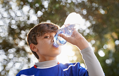 Buy stock photo Shot of a young boy in sports clothing drinking from a water bottle