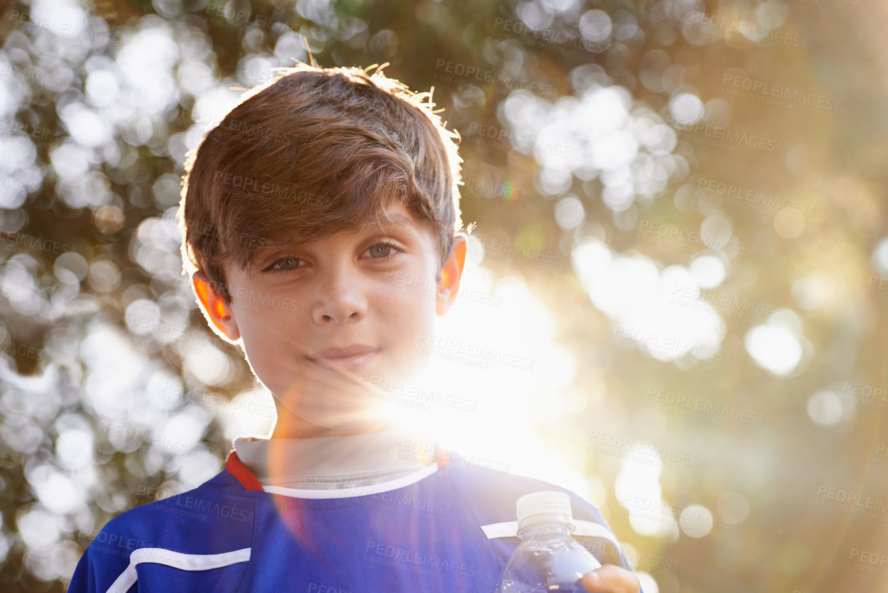 Buy stock photo Child, portrait and outdoor sports training in nature for soccer practice in exercise kit, competition or match. Male person, face and sunlight as athlete with water drink or activity, summer or game
