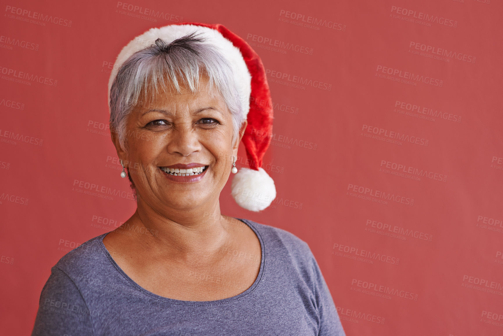 Buy stock photo Portrait, smile and Christmas hat with senior woman, retirement and happiness on red studio background. Face, old person and elderly lady with joy or Xmas with celebration, cheerful or festive season