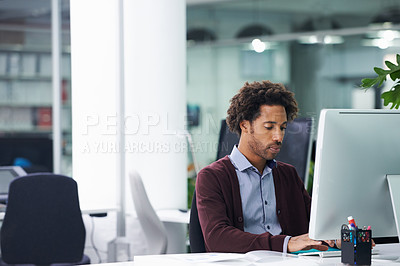 Buy stock photo Shot of a young businessman sitting at a desk