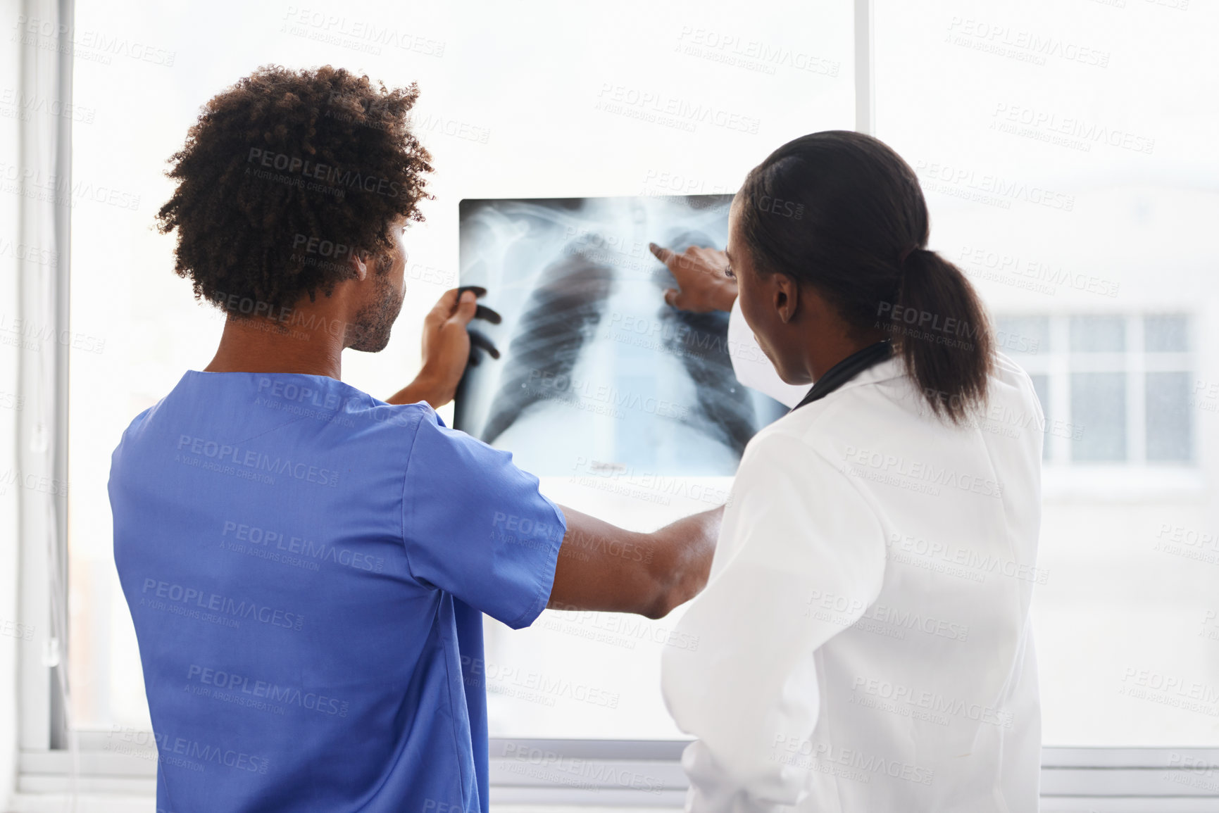 Buy stock photo Shot of a female doctor and male nurse studying x-rays