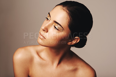 Buy stock photo Studio shot of a beautiful woman looking away while wearing nothing but gold make up