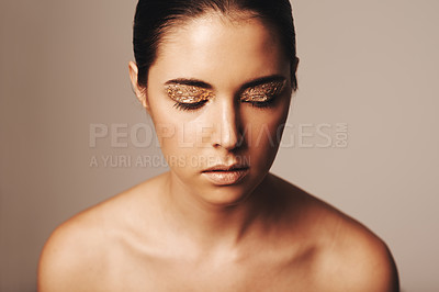 Buy stock photo Woman, makeup and gold glitter on eyes for beauty, cosmetology and glamour with cosmetics on beige background. Eyeshadow, elegance and face model in studio, art or creativity with shimmer and glow