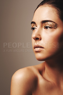 Buy stock photo Studio shot of an attractive brunette wearing gold make up and looking away