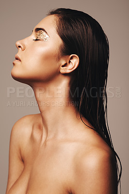 Buy stock photo Studio shot of a glamorous young woman with closed eyes wearing gold make up