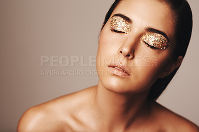 Buy stock photo Studio shot of a beautiful woman with eyes closed and gold eye makeup