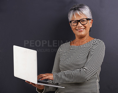 Buy stock photo Laptop, typing and portrait of mature woman in studio background learning about technology or website. Senior, person and education on computer for communication, connection and social networking