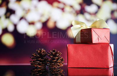 Buy stock photo Shot of Christmas gifts and pine cones on a table with Christmas lights in the background