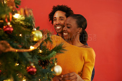 Buy stock photo Couple, Christmas and tree decoration in home with happiness for vacation celebration, giving or bonding. Man, woman and smile with lighting for winter season for family event, embrace or lounge