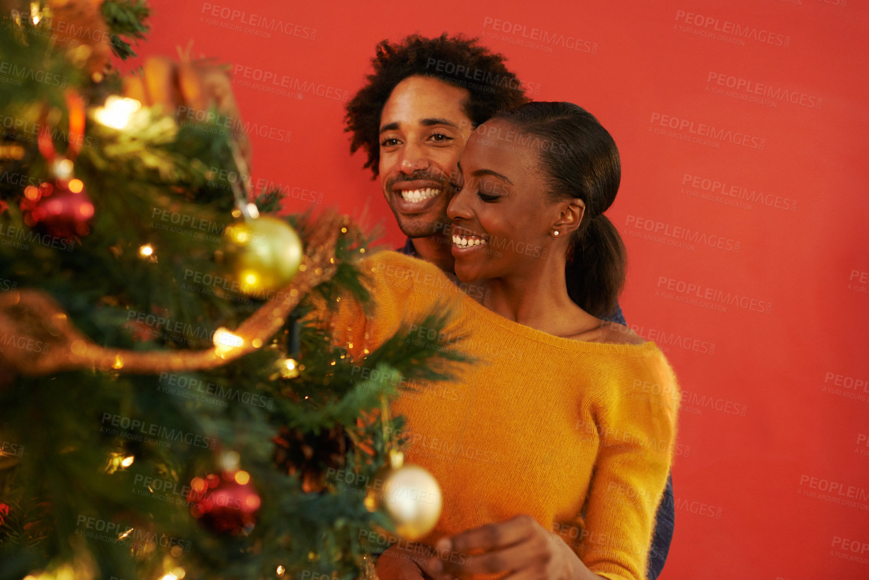 Buy stock photo Couple, Christmas and tree decoration in home with happiness for vacation celebration, giving or bonding. Man, woman and smile with lighting for winter season for family event, embrace or lounge