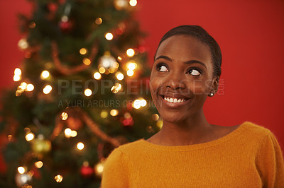Buy stock photo Shot of an attractive young woman standing in front of a Christmas tree