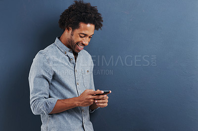 Buy stock photo Businessman, cellphone and texting in studio for online connection on blue background, mockup or typing. Male person, smile and internet or reading email or communication, message or social media