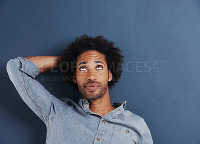 Buy stock photo Shot of a handsome young man looking up at copyspace on a gray background