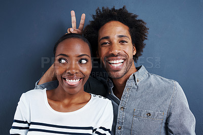 Buy stock photo Happy, portrait and black couple with peace and love on studio background together with happiness. Crazy, face and sign for bunny ears in silly profile picture of people with casual fashion or style