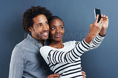 Buy stock photo Happy, love and couple with selfie in studio for care, trust or bonding against a grey background. Smile, app and people hug for blog photography, profile picture or romantic social media memory