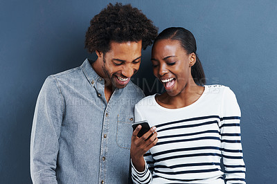 Buy stock photo Black couple, funny and smartphone with meme, smile and social media on a blue studio background. Mockup space, mobile user and man with woman and cellphone with online reading and video with humor