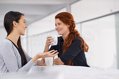 Buy stock photo Two female colleagues chatting over coffee during their break
