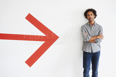 Buy stock photo Man, portrait and arms crossed with arrow by wall in car park with confidence, mockup space and travel. African person, face and serious tourist in parking area with direction, sign and symbol